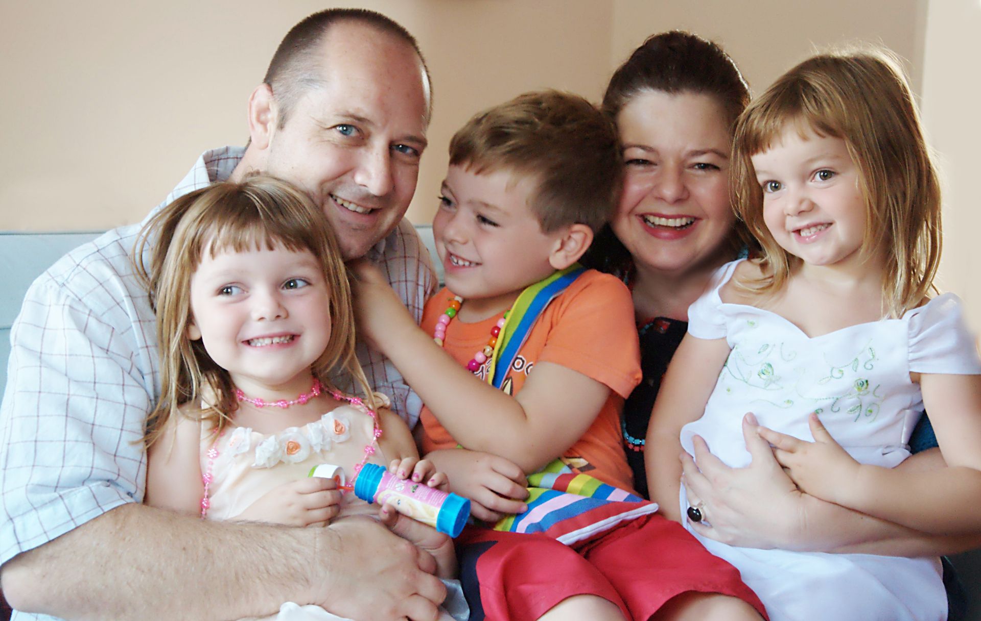 A family is posing for a picture while sitting on a couch.