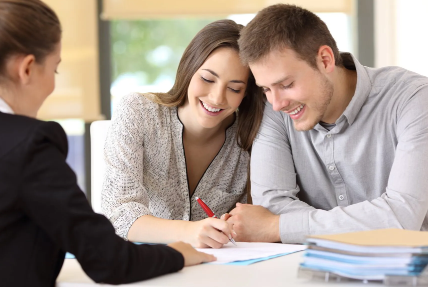 A man and a woman are sitting at a table signing a document.