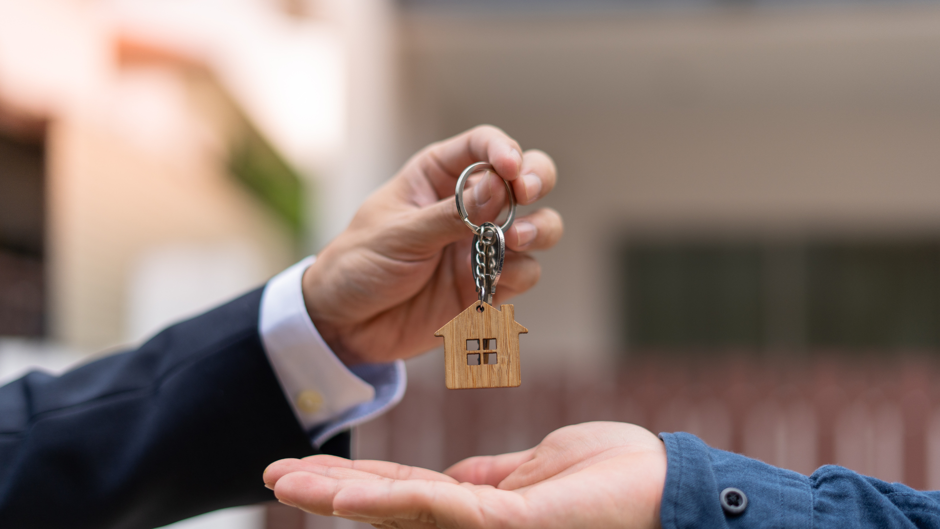 A man is handing a house key to another man.