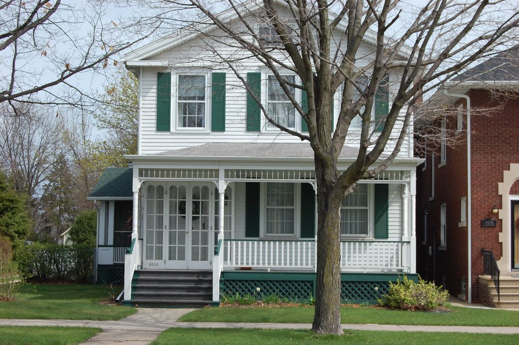 A white house with green shutters and a porch
