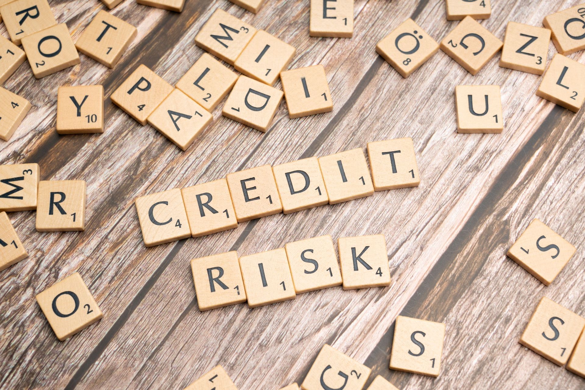 Scrabble tiles spelling “credit risk” on a rustic wooden surface