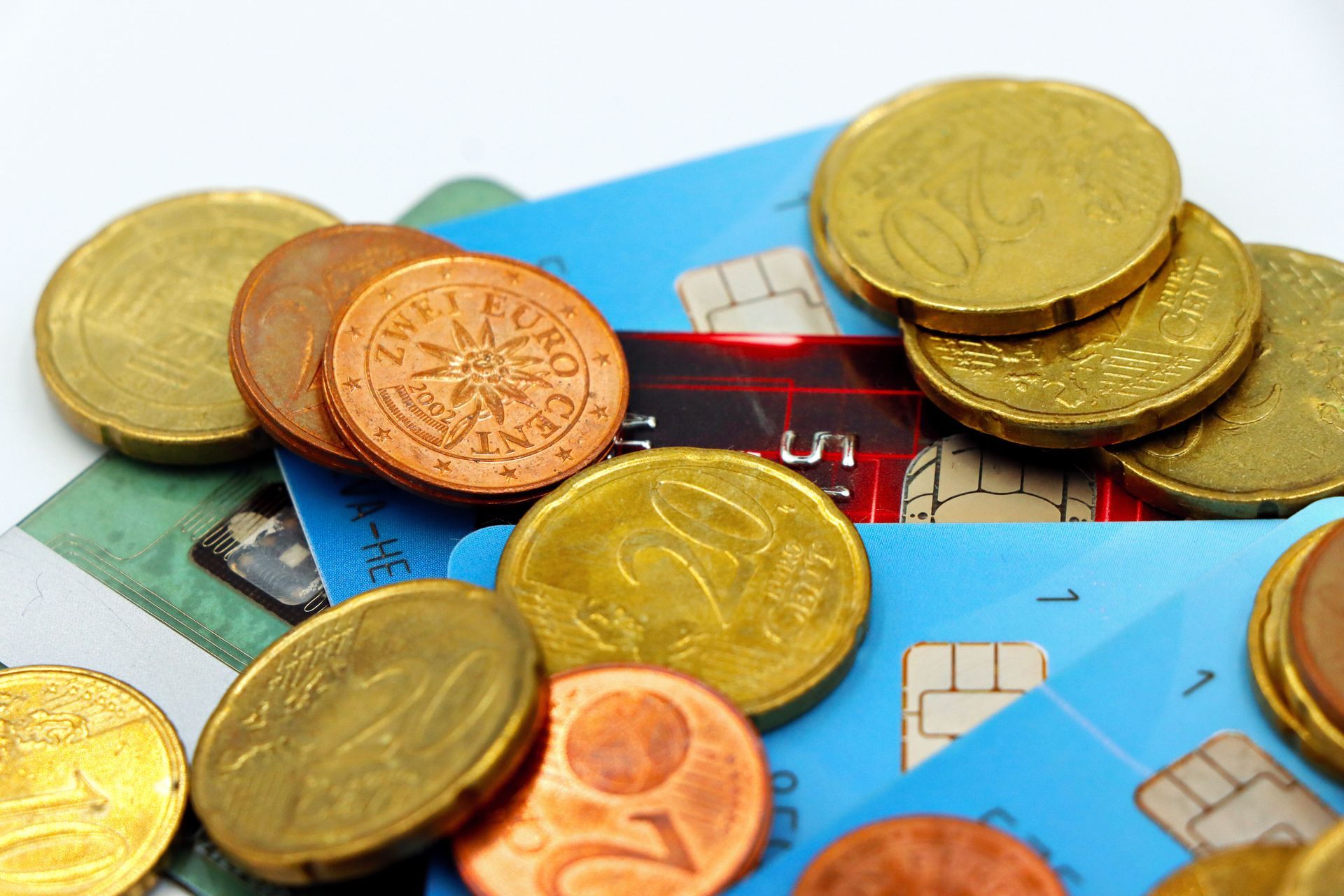 Gold and copper coins scattered on colorful credit cards, suggesting money and banking.