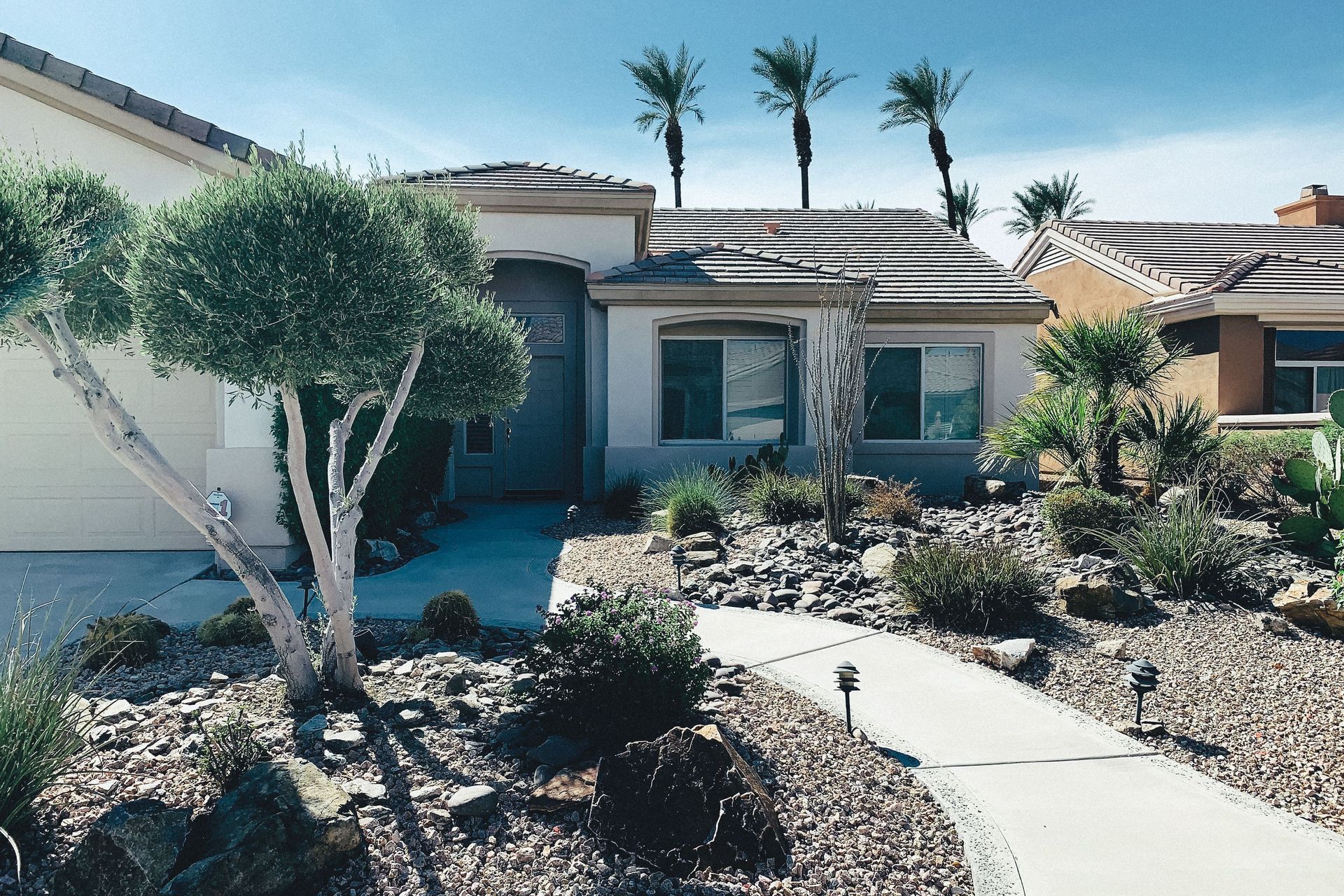 Single-story house with desert landscaping and a curved front walkway
