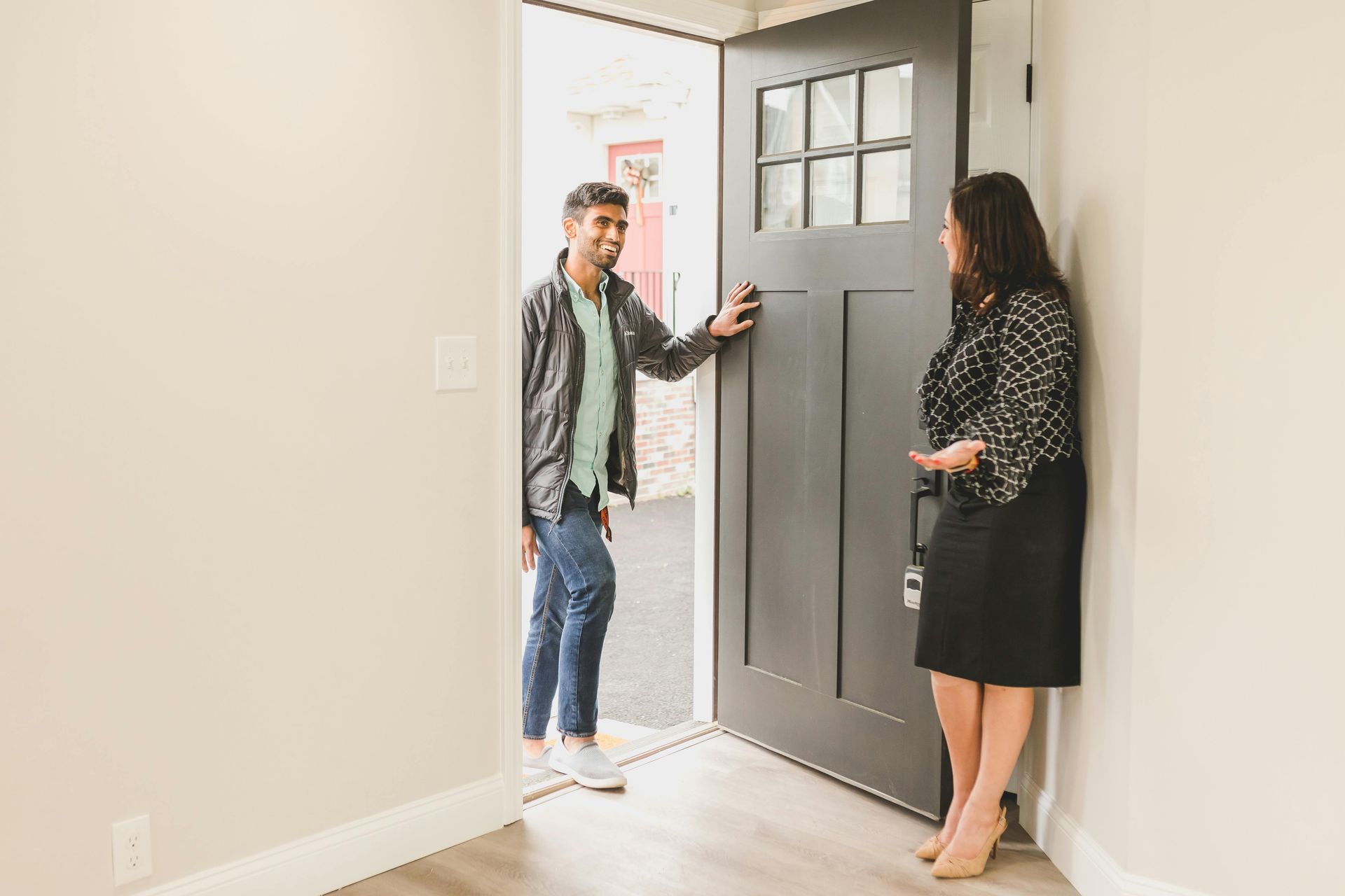 Two people standing by an open front door in a bright entryway