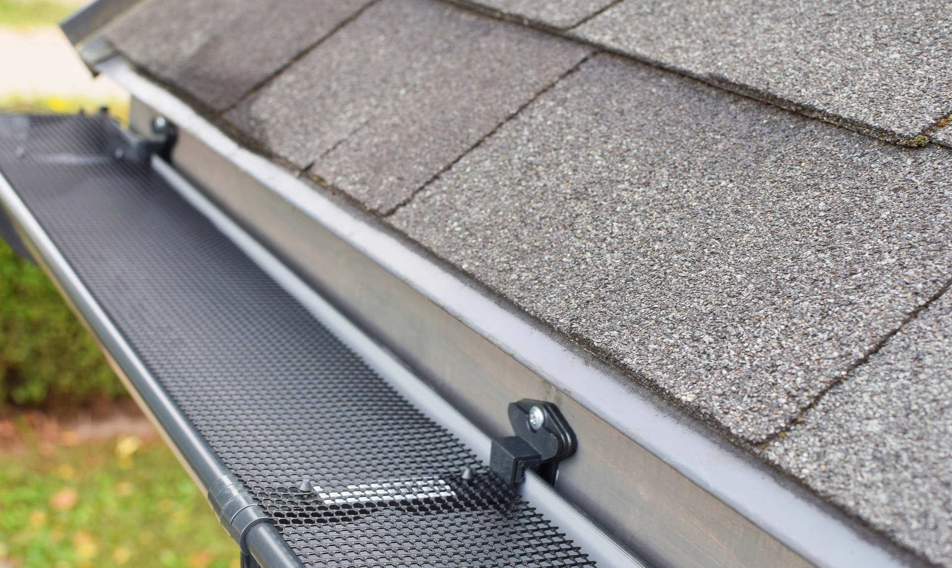 Gutter guard on a roof: black mesh over a metal gutter, protecting against debris.