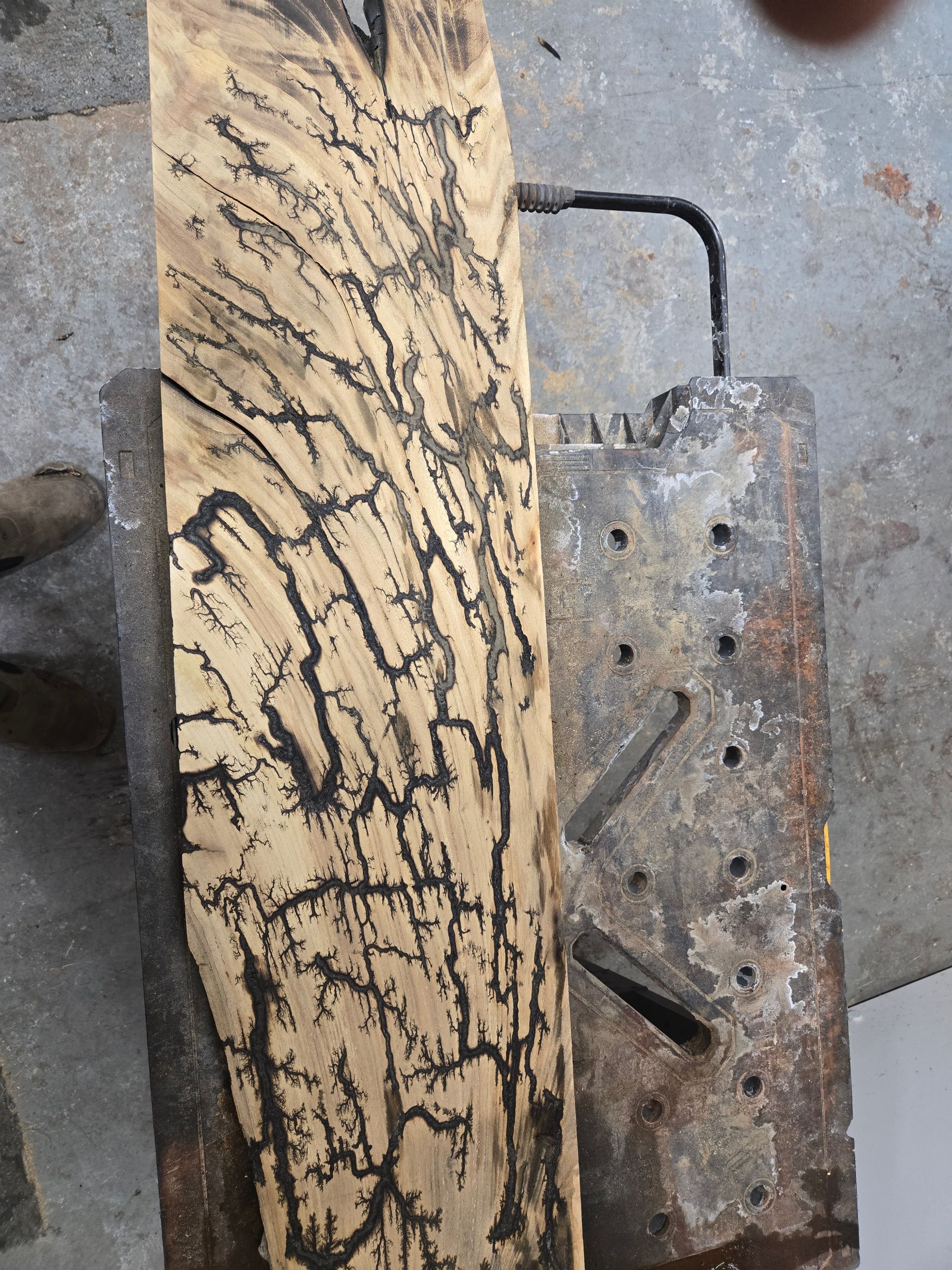 A wooden board featuring black, branching fractal patterns created by a Lichtenberg wood burning technique.