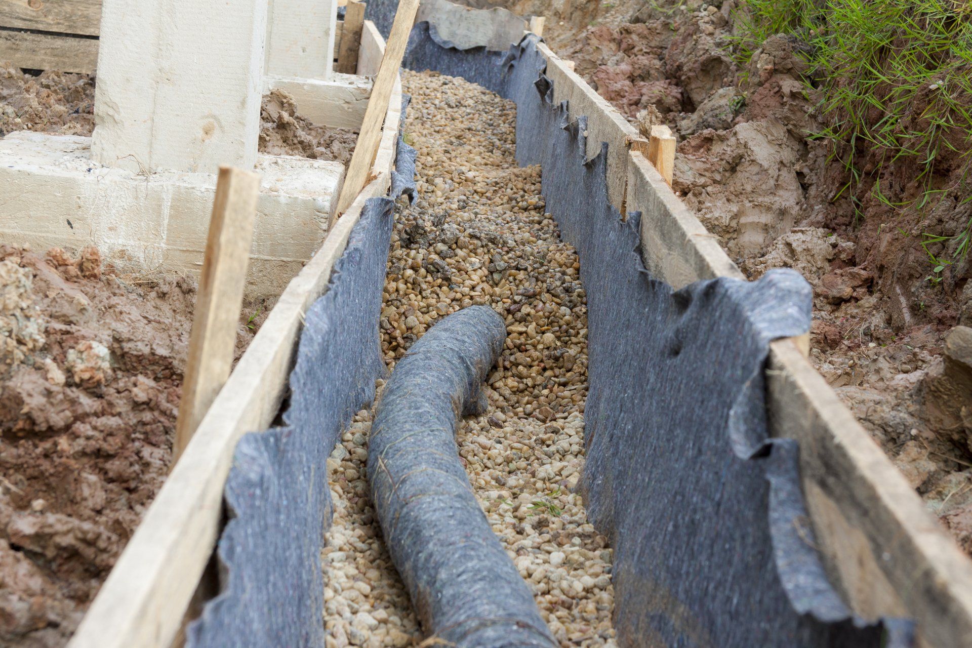 Un tuyau est en cours d'installation dans une tranchée remplie de gravier.