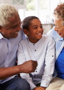 Grandparents smiling with a child in a home setting.