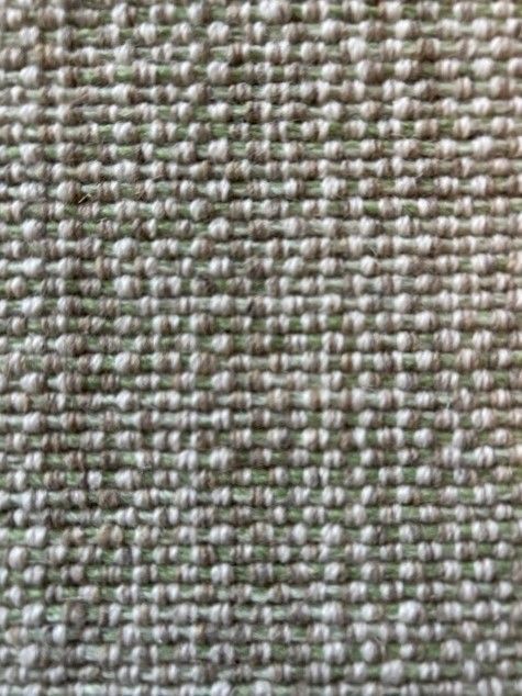 Close-up of a woven fabric with a textured surface of light green and white.