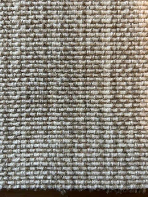 Close-up of a textured, light beige fabric. Horizontal, rectangular woven pattern.
