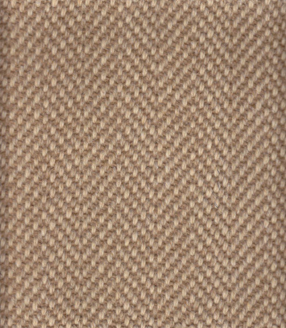 Beige herringbone patterned carpet texture.