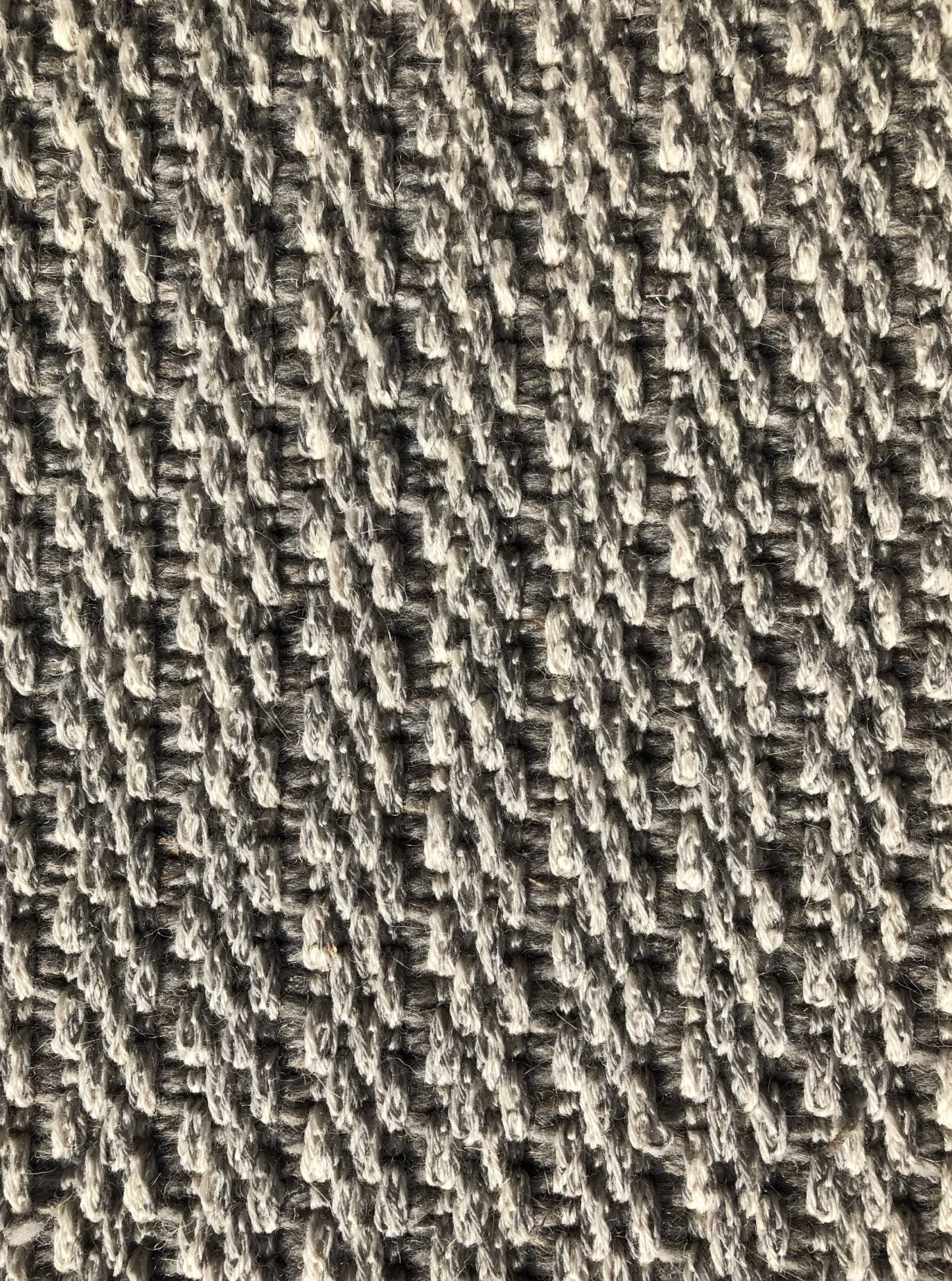 Close-up of a woven fabric with a diagonal pattern in shades of gray and white.