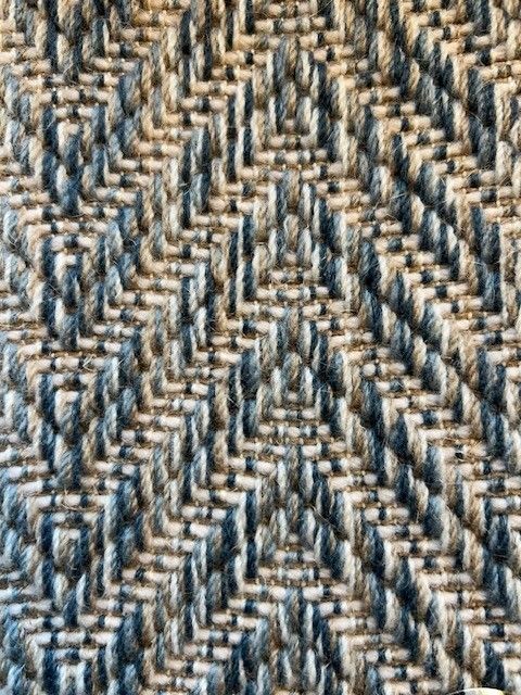 Close-up of a woven textile with a geometric, zigzag pattern in shades of blue and tan.
