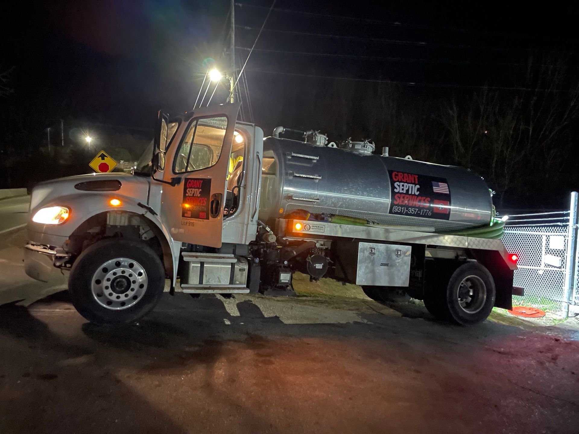 A tanker truck is parked on the side of the road at night.