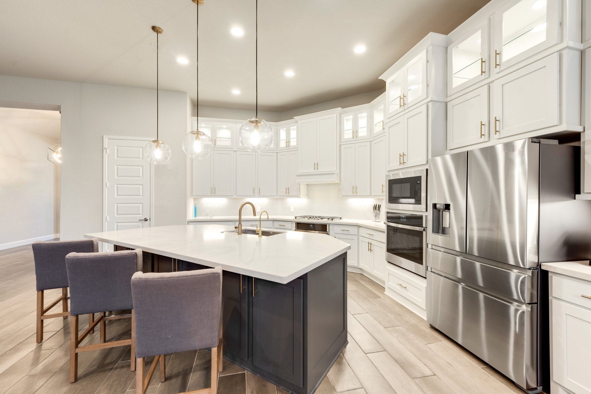 A kitchen with white cabinets , stainless steel appliances , and a large island.