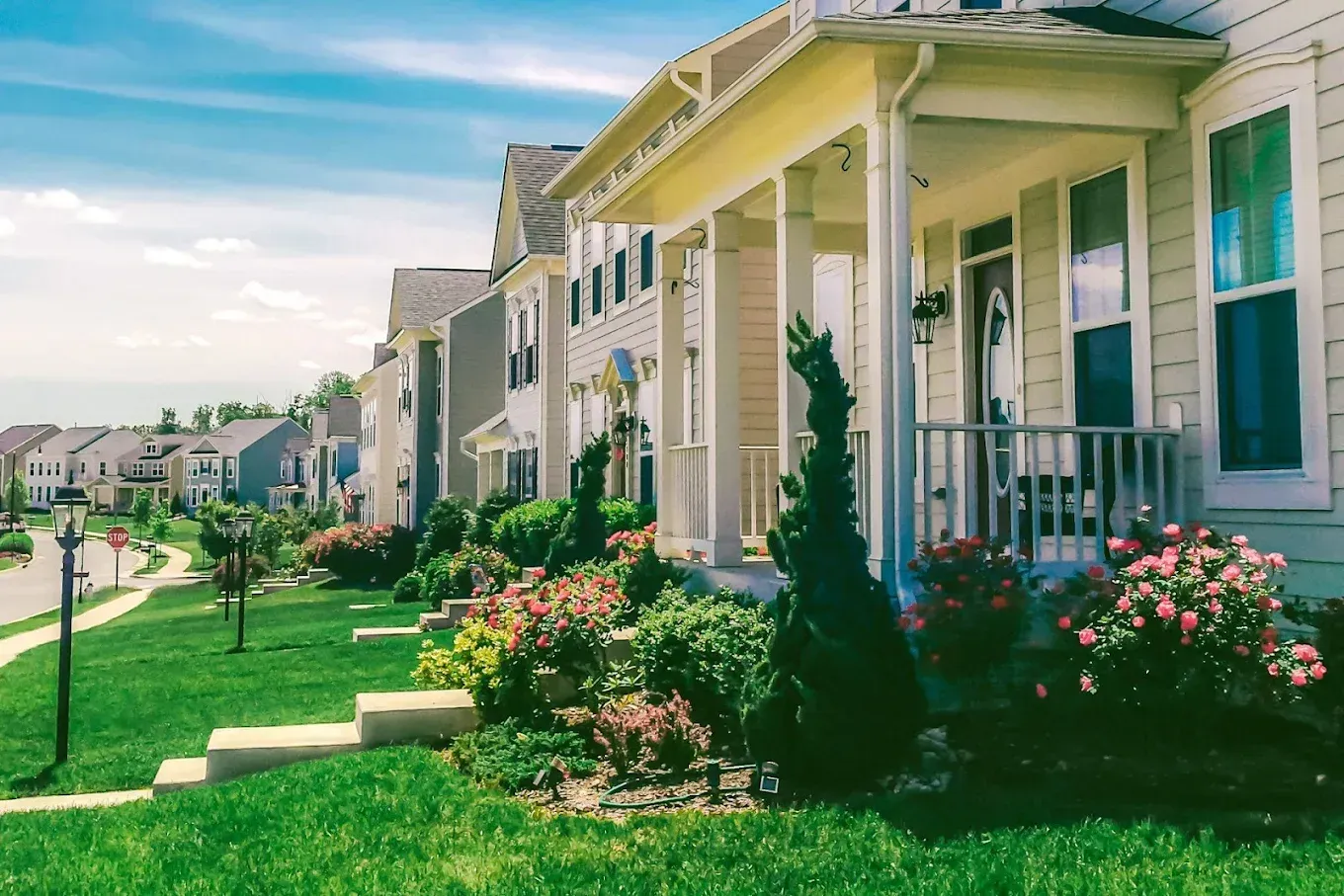A row of houses in a residential neighborhood with a lush green lawn.