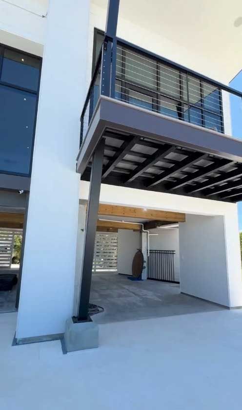 A white building with a balcony and a garage underneath it.