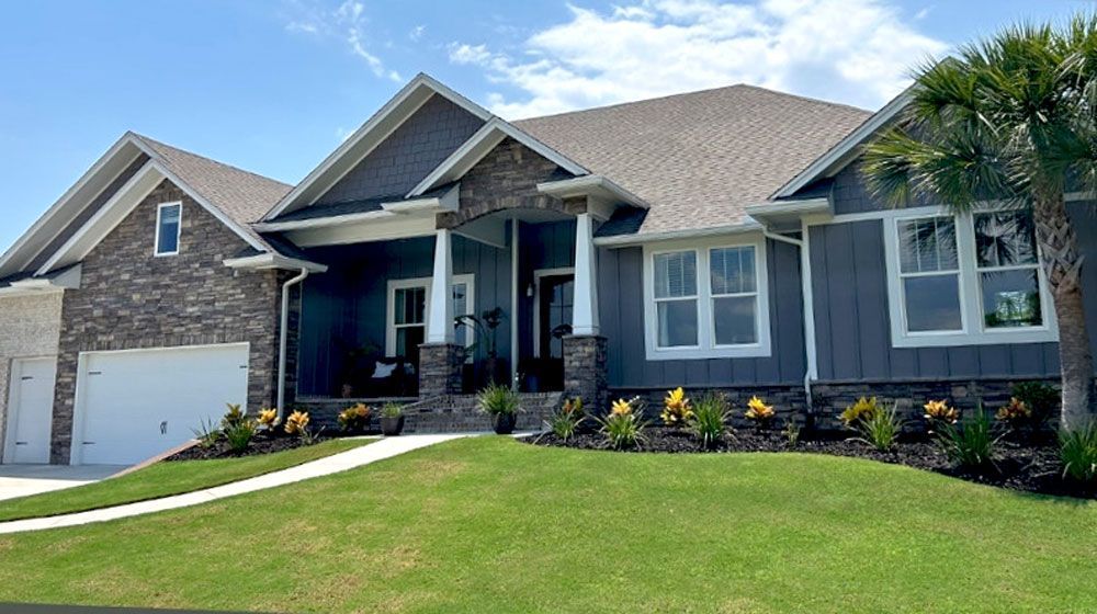 A large house with a lot of windows is sitting on top of a lush green hill.