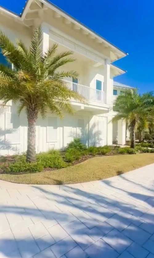 A large white house with palm trees in front of it.