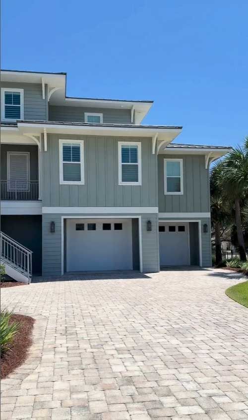 A large house with two garages and a brick driveway.