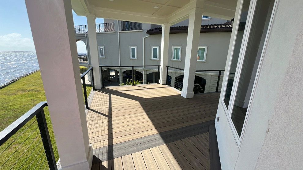 A large deck with a view of the ocean and a house in the background.