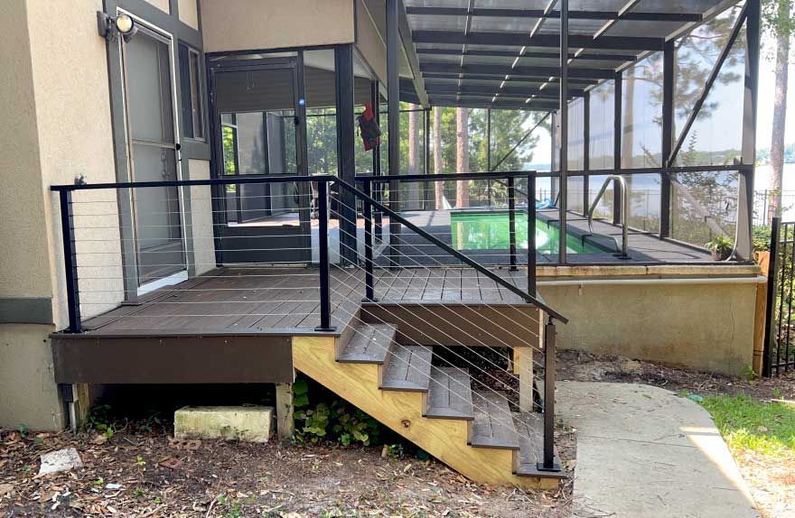 A deck with stairs leading up to a screened in pool.