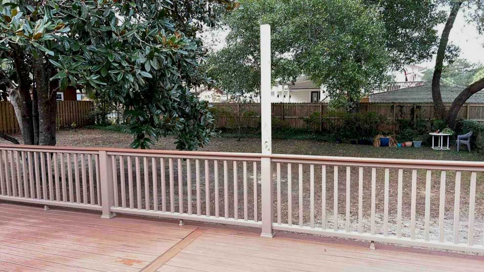 A wooden deck with a fence and trees in the background.