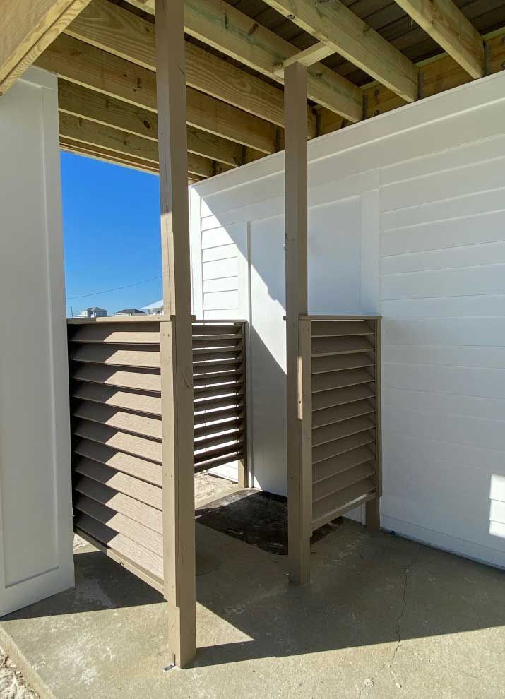 A row of outdoor showers under a wooden roof.