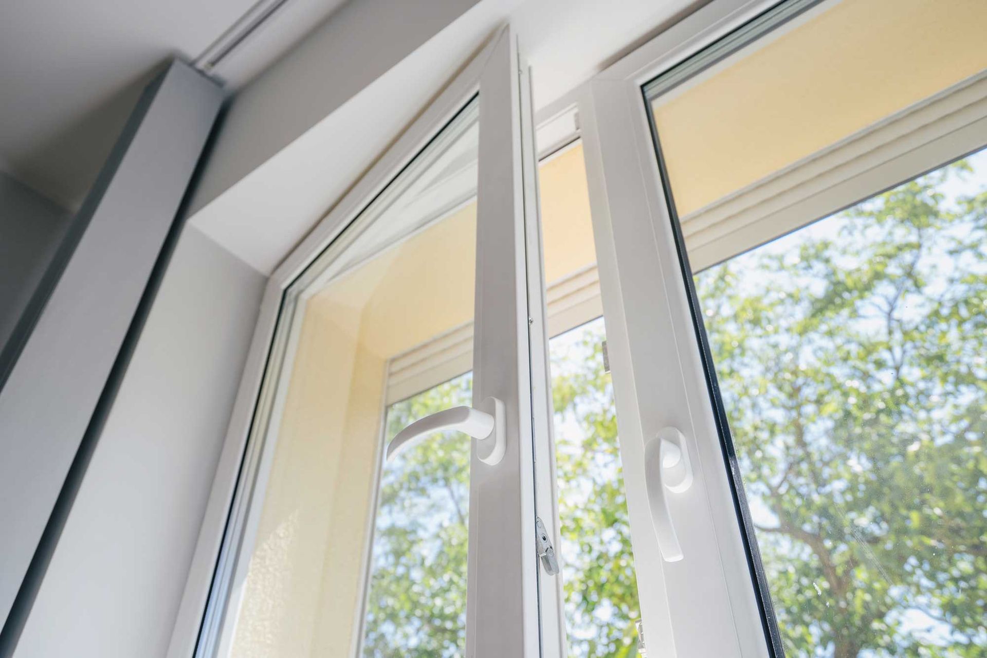 A close up of an open window with trees in the background.