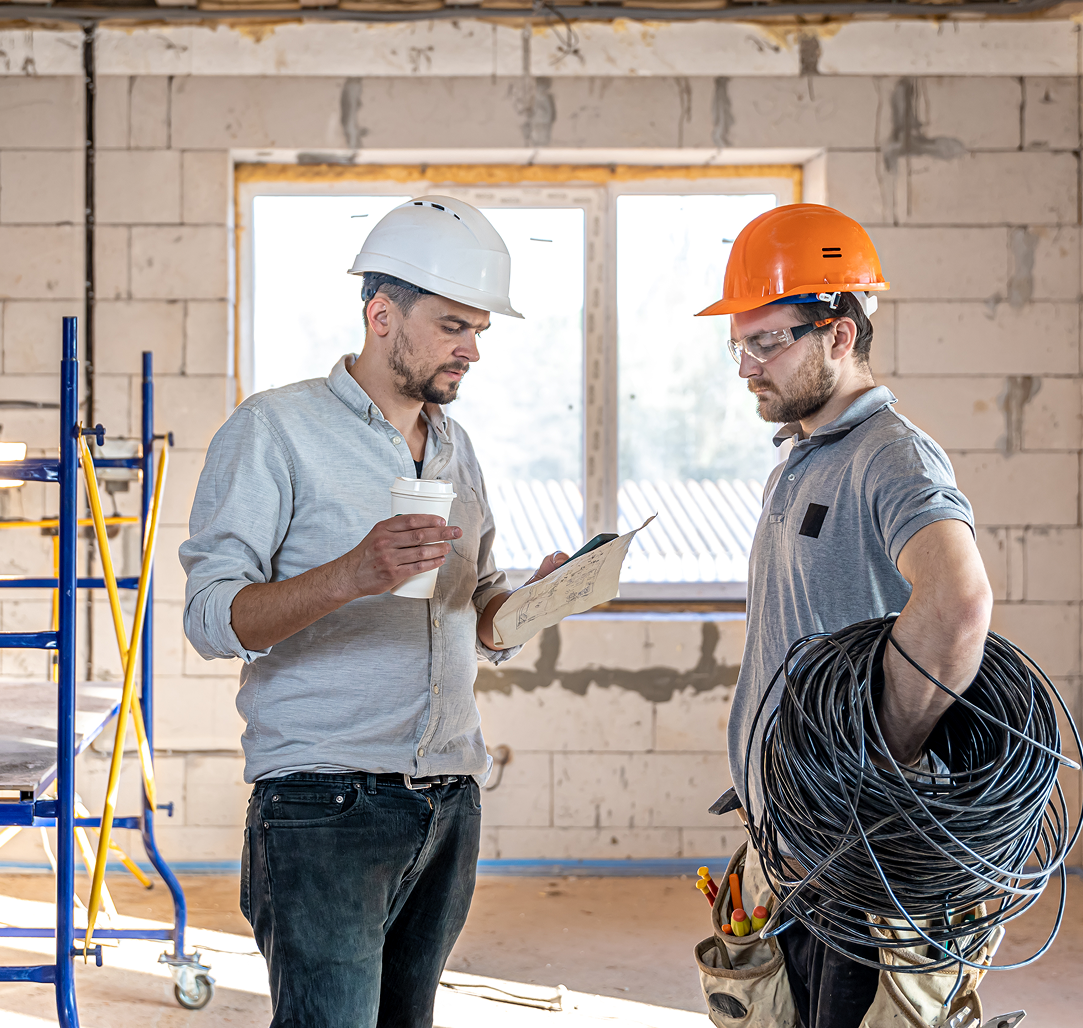 A group of construction workers are sitting around a table with hard hats.