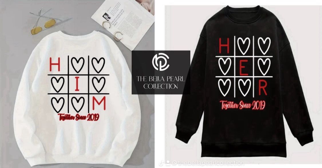 A white sweatshirt with hearts on it and a black sweatshirt with hearts on it.