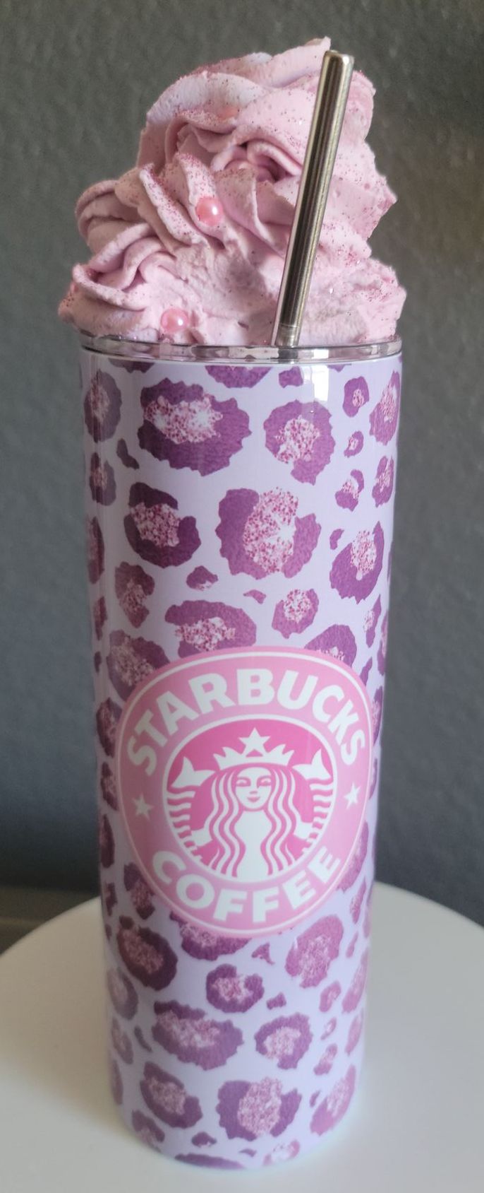 A purple starbucks tumbler with pink whipped cream on top.