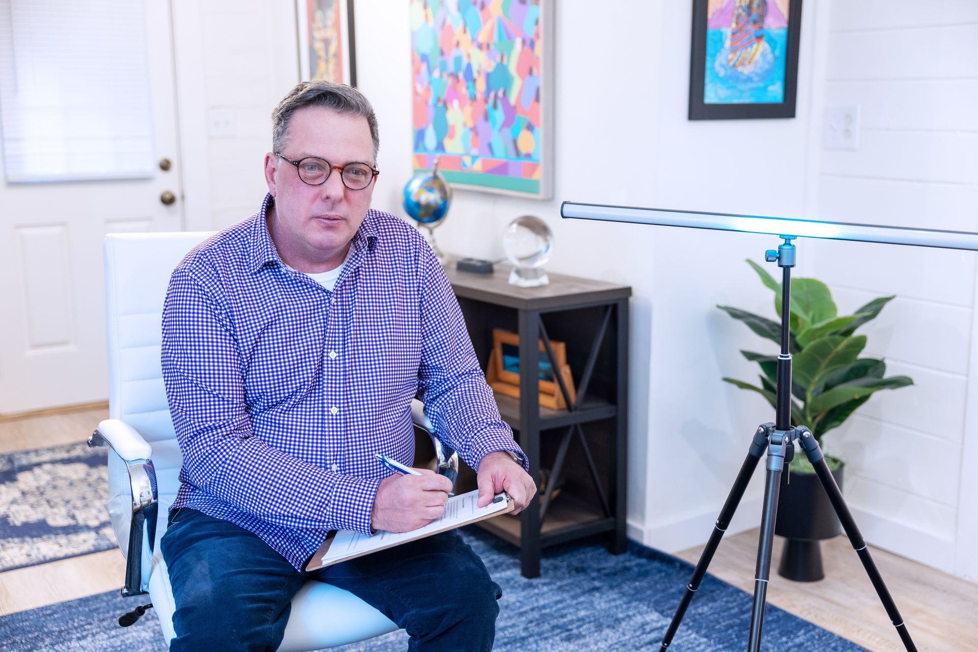 Therapist with notepad listens to a person reclining on a couch, gesturing and talking.