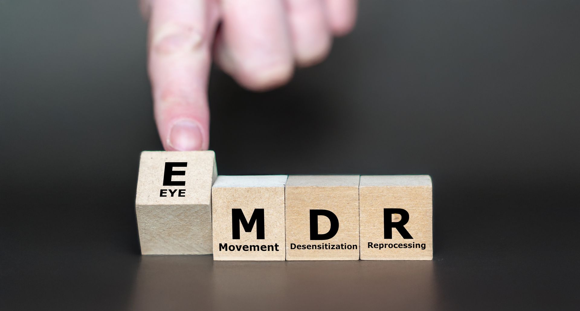 Person's finger touching a wooden block with the letter