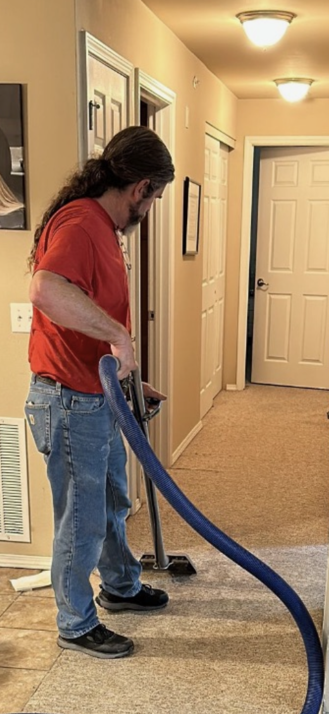 A woman is using a vacuum cleaner to clean a rug in a living room.