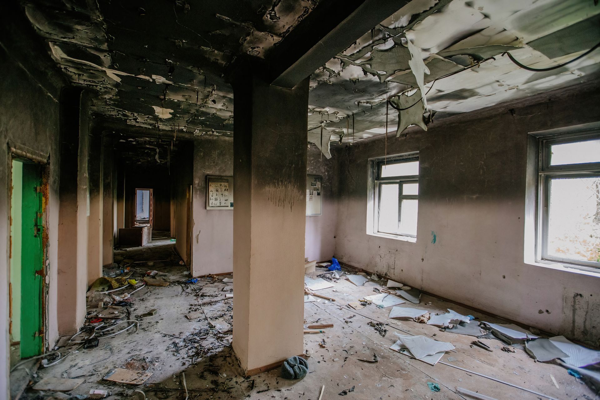 An empty room in an abandoned building with a green door.