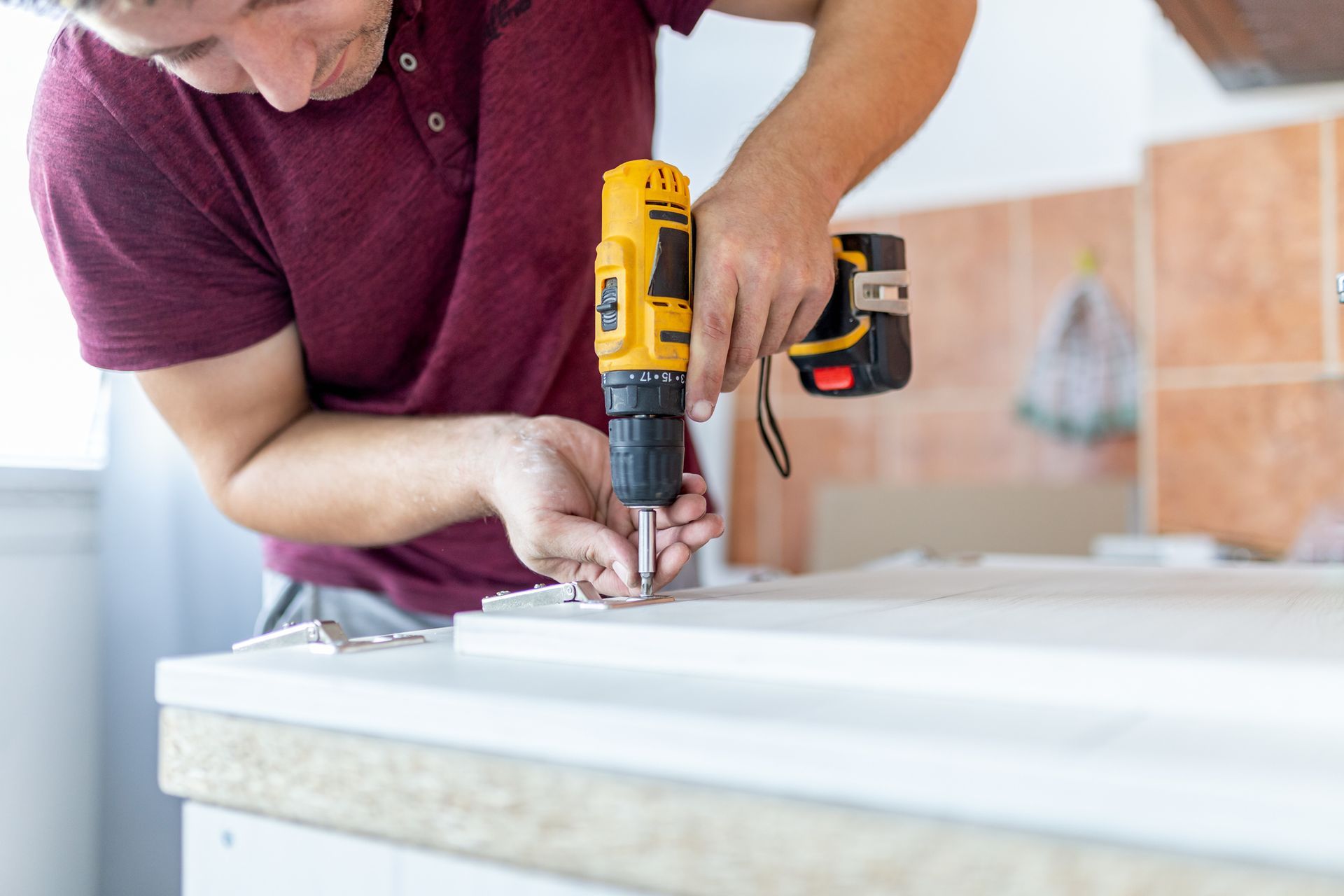 A man is using a drill to drill a hole in a piece of wood.