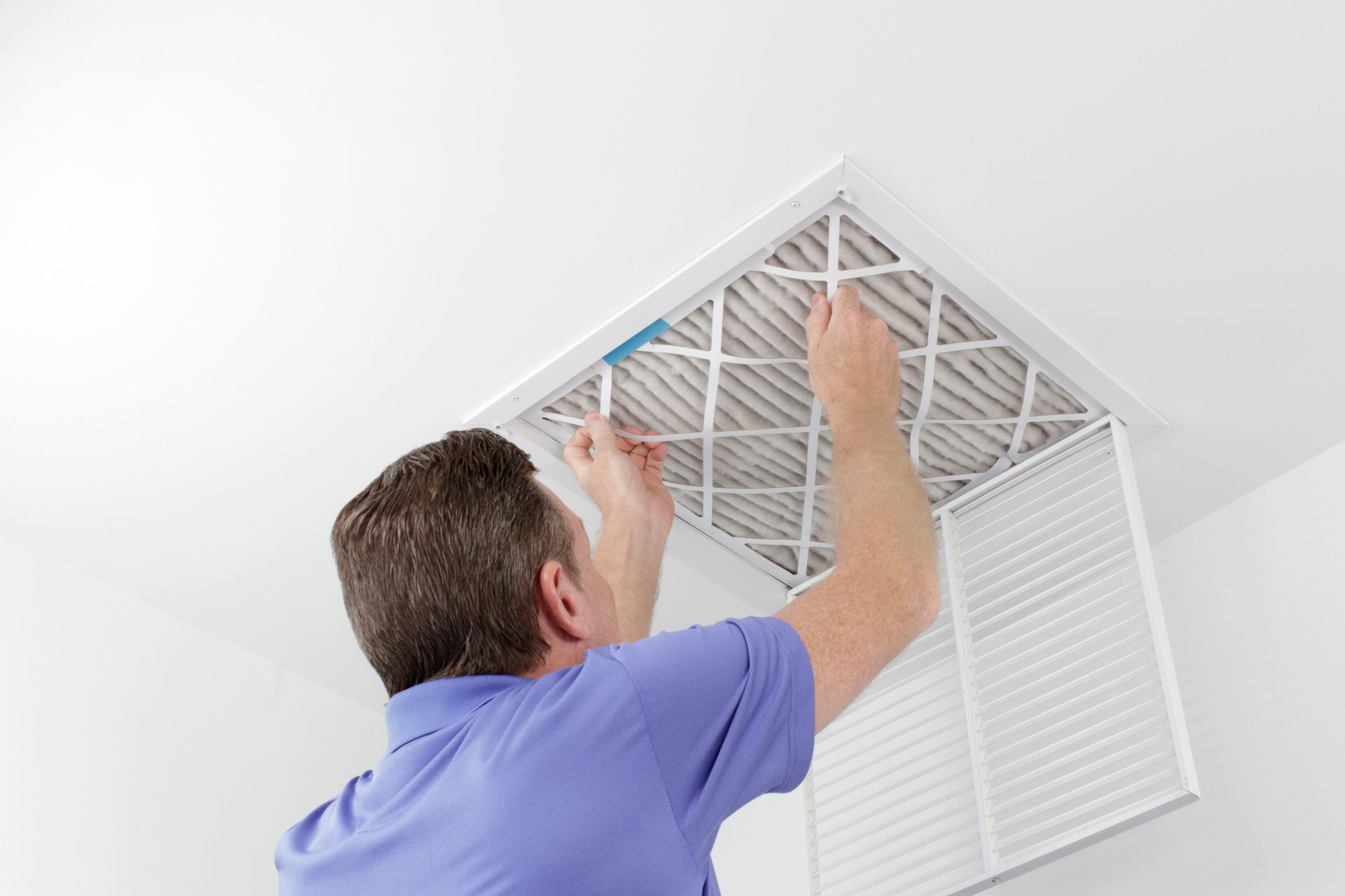 A man is installing a filter on the ceiling of a room.