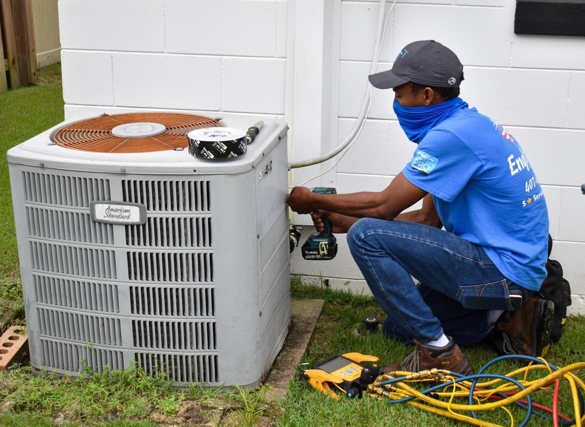 Two technicians in blue shirts servicing an outdoor English Air HVAC unit