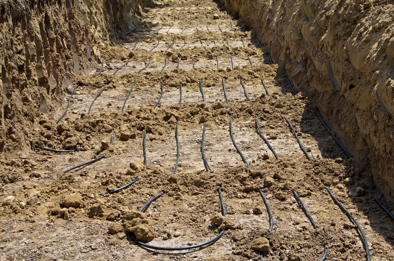 Excavated trench with exposed rebar and dirt walls along a stepped cut in the ground
