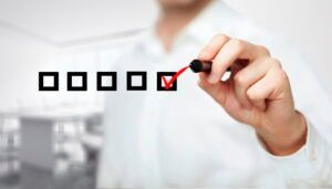 Hand checking a red checkbox in a row of black checkboxes on a white background
