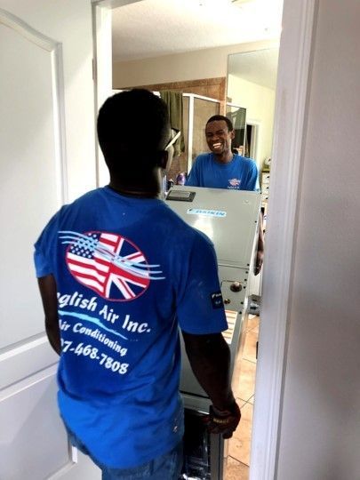 Worker in blue shirt stands by a mirror, seen from behind in a hallway.