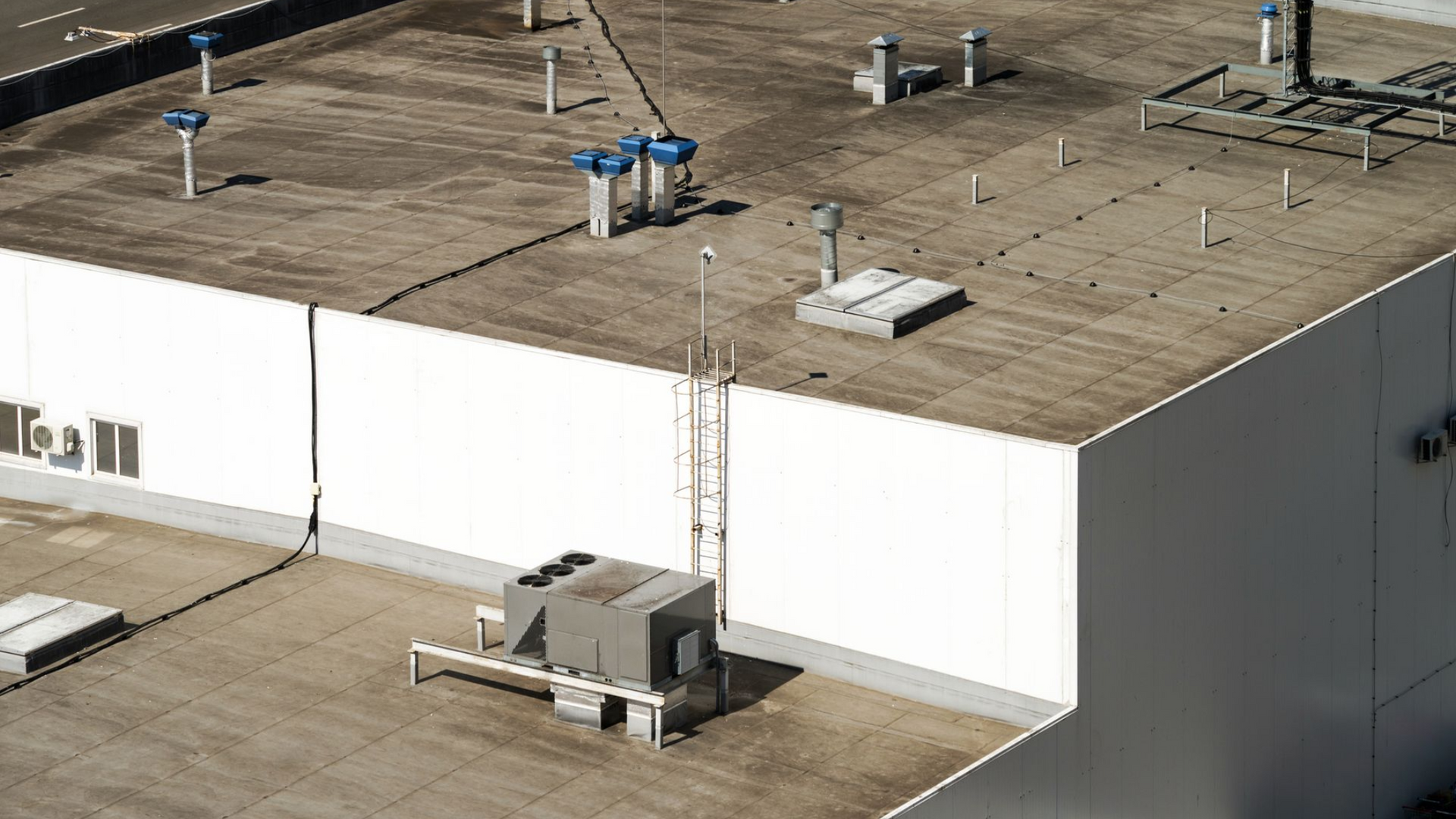 Aerial view of a white industrial warehouse roof with vents and HVAC units.