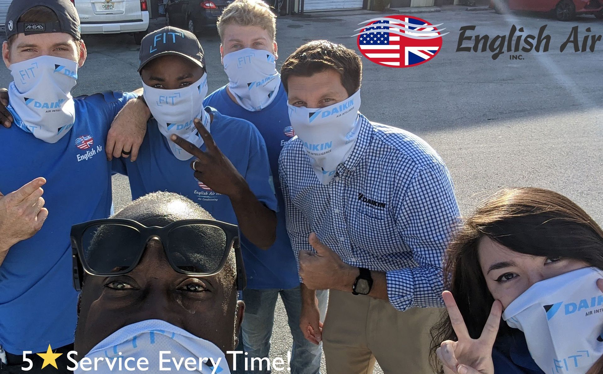 Five masked people pose outdoors near an English Airways sign, making peace signs.