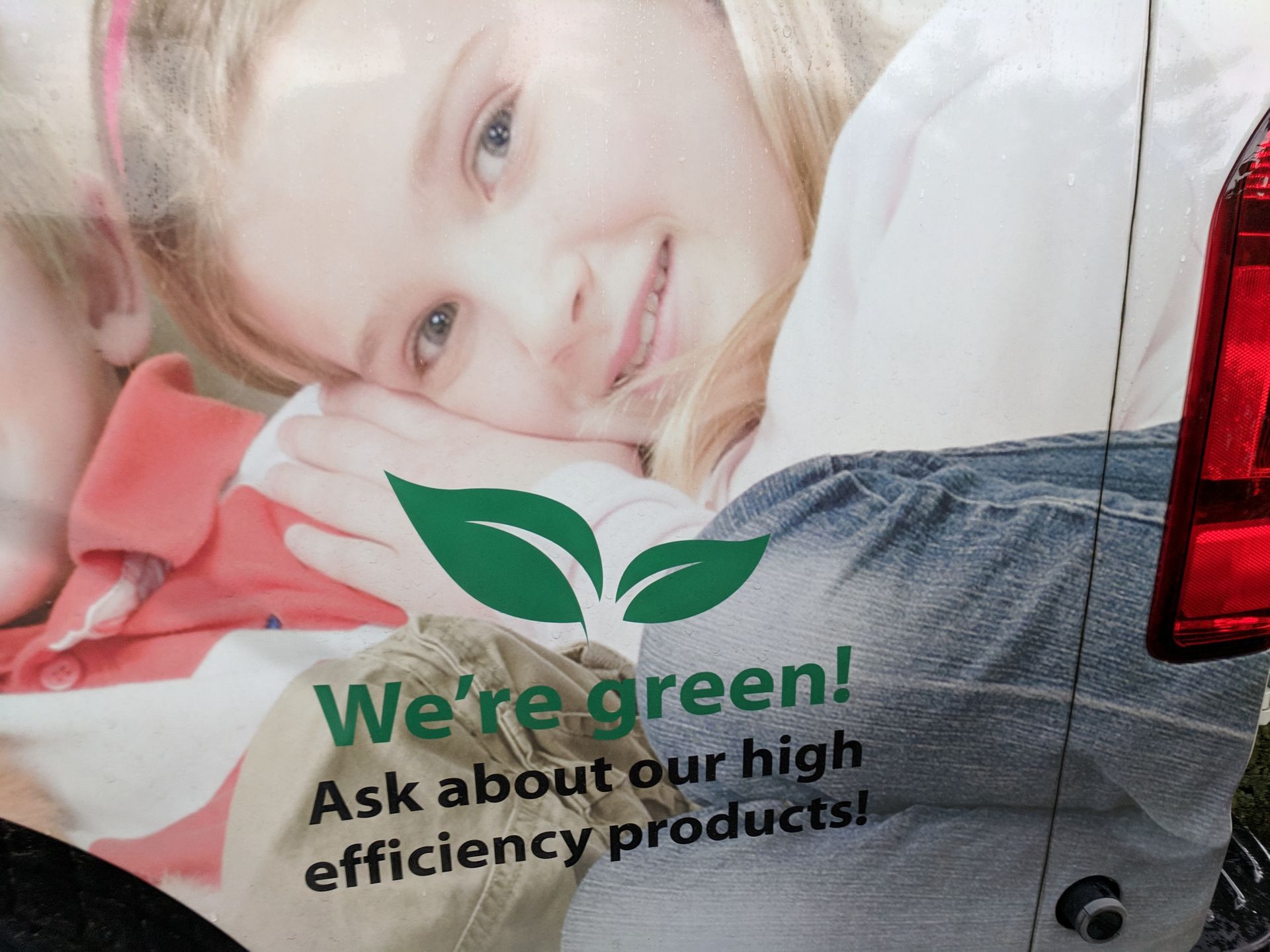 Green promotional banner with a smiling child and the text “We’re green! Ask about our high efficiency products!”