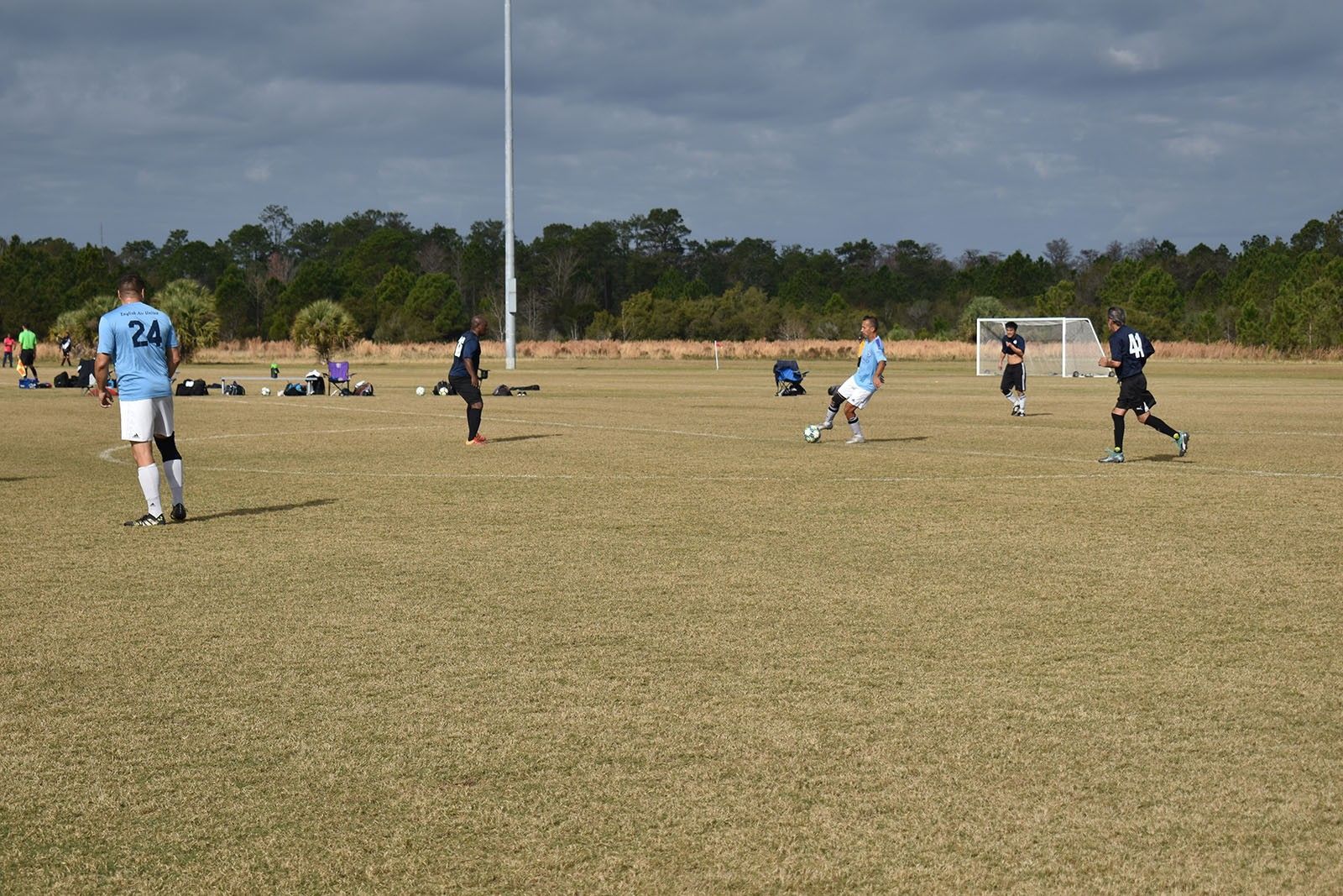 Soccer game on a dry field, with players in blue and black near the goal.