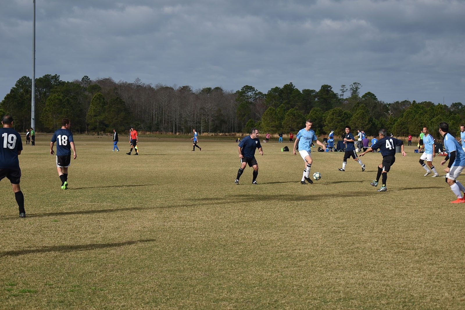 Soccer players in blue and black uniforms running on a grassy field during a match