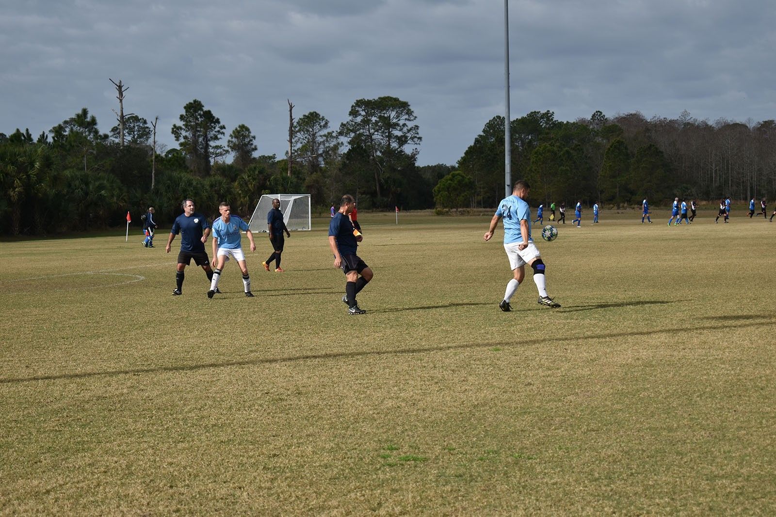 Soccer players in blue and dark uniforms on a grassy field during a game