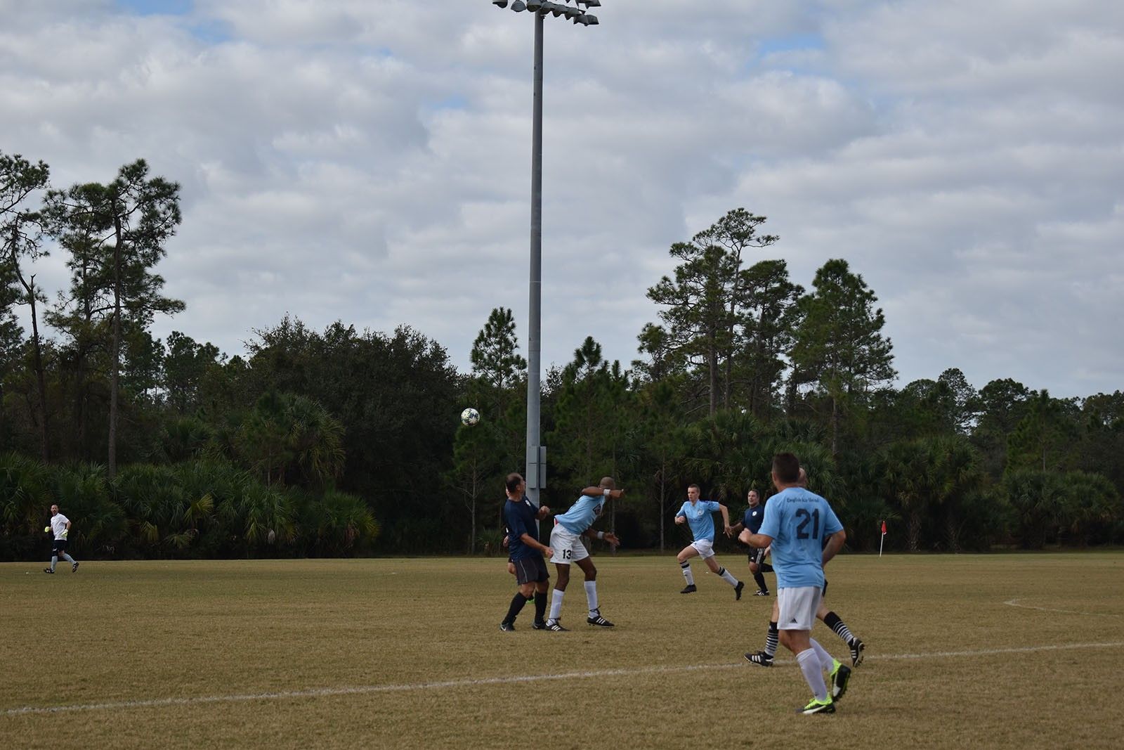 Soccer players in blue jerseys on a field, with one kicking the ball near the goal area.
