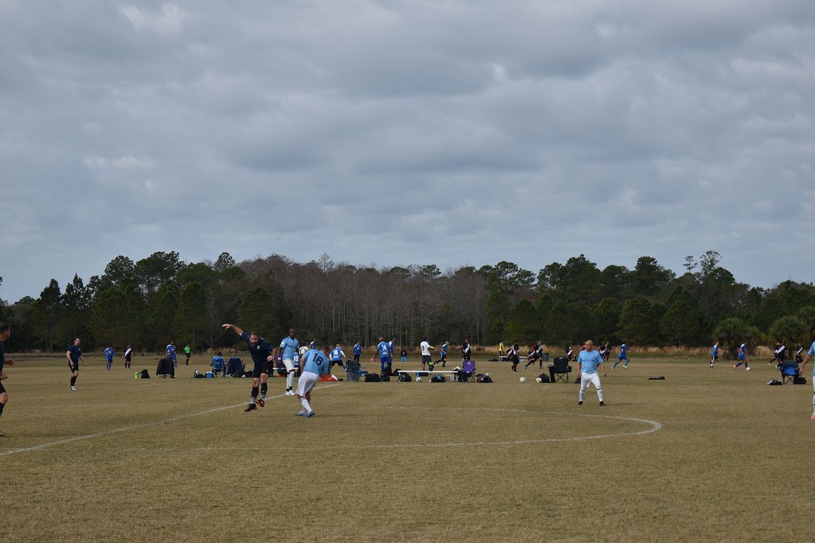 Soccer players in blue uniforms on a grassy field under a cloudy sky